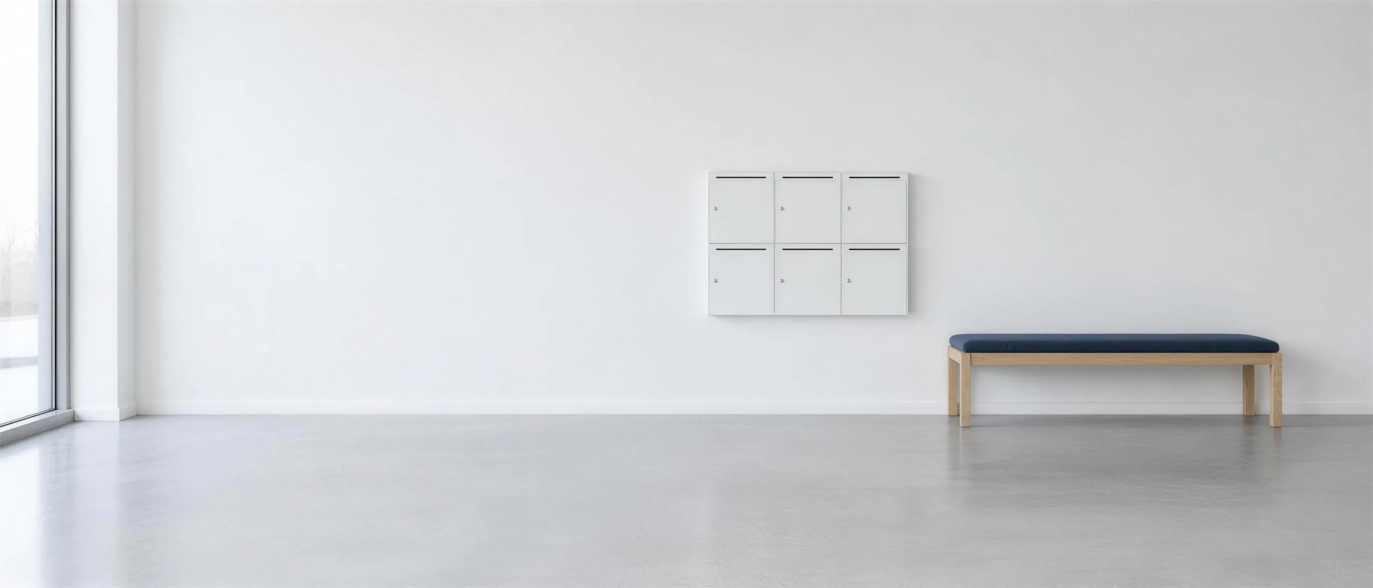 Letterboxes on the wall of a bright entrance area, in front of them a bench with dark blue upholstery